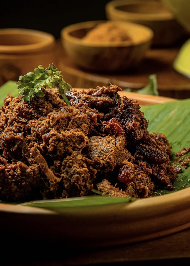 Rendang Daging Sapi or Beef stew traditional food from Padang, Indonesia. The dish is arranged among the spices and herbs used in the original recipe like chili, lemongrass onion